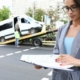 Insurance agent standing near wrecked car on tow truck