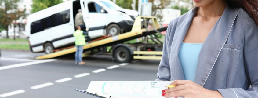 Insurance agent standing near wrecked car on tow truck