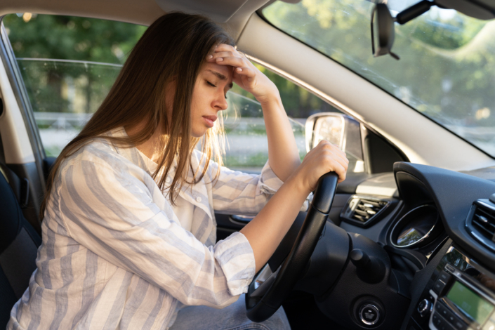 Tired young woman car driver suffer from headache or migraine pain inside vehicle touch forehead