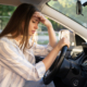 Tired young woman car driver suffer from headache or migraine pain inside vehicle touch forehead