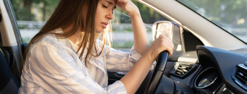 Tired young woman car driver suffer from headache or migraine pain inside vehicle touch forehead