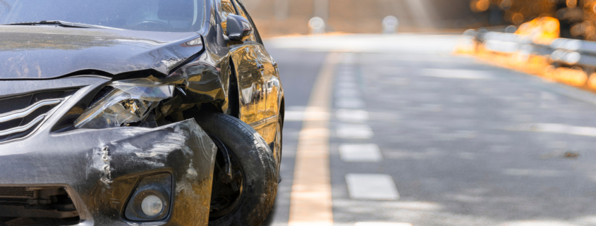 Artumn road. Front of black color car big damaged and broken by accident on road parking can not drive any more. With copy space for text or design