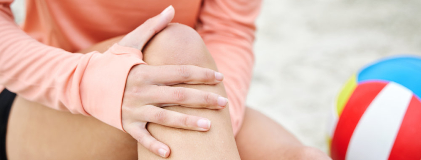 Knee pain, woman hands and beach volleyball injury of a athlete on sand with sport accident. Fitness, exercise and training bruise by the sea and ocean with muscle strain from workout and running.