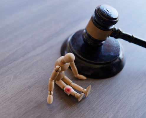 Bandage wrap with blood stain, wooden doll and judge gavel. Personal injury law concept.