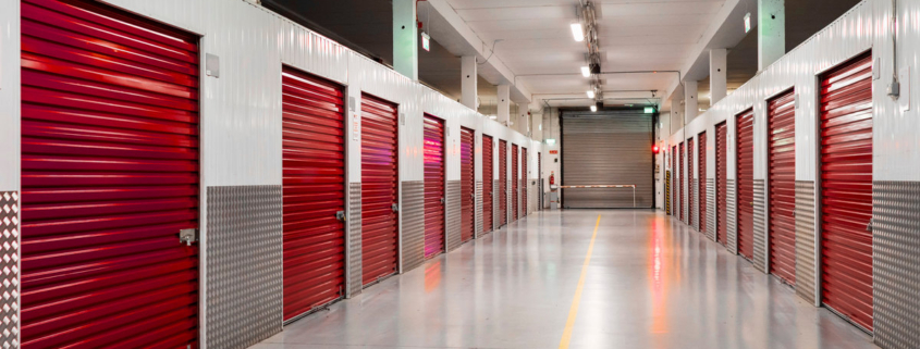 Long row of red color doors of self storage facility. Service to keep safe extra belongings. Nobody. Selective focus. Clean and well run business.