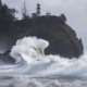 Powerful ocean wave crashing under lighthouse during king tide storms on the Washington coast, Cape Disappointment