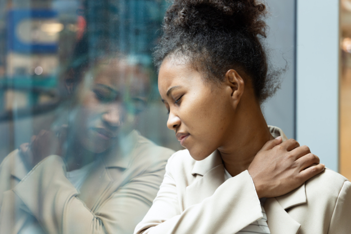 African office worker woman having shoulder sickness or neck pain from overwork or office syndrome