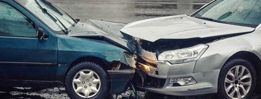 Car accident on wet road during rain, head on collision side view. Two cars damaged after head-on collision, car crash. Car crash on the street, damaged cars after collision. Traffic rules violation