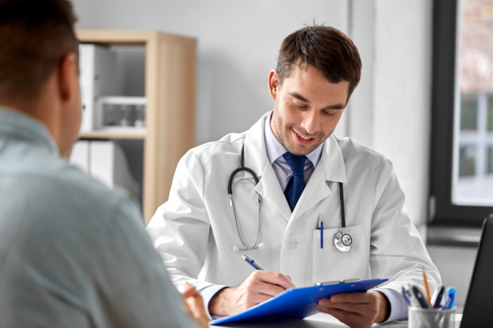 Doctor with clipboard talking to a patient during an exam